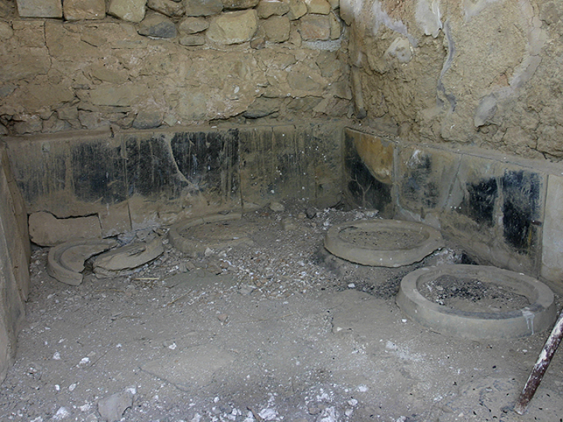 Lagerraum mit Fundamenten für die Vorratsgefäße (Pithoi) und sichtbaren Brandspuren.