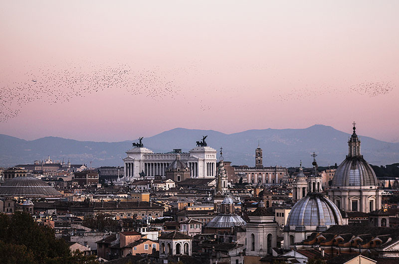 Pastellfarben schwindet das Licht - Traumhaft. Gut erkennbar ist links die Pantheon-Kuppel, in der Mitte der Vittoriale und das Kapitol. Am Himmel erkennbar sind Schwärme von Staren die am Himmel ihre Abendrunde drehen.