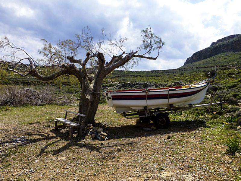 Einsame Bank, einsamer Baum und ein einsames Boot am Amatos-Strand.