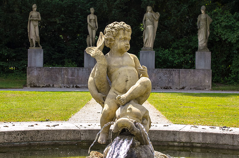 Hinter dem Delphinbrunnen sind weitere Skulpturen aufgestellt. Sie zeigen Paris mit dem Apfel als Gegenstand des Streits, Aphrodite, Hera und Pallas Athene (von links nach rechts).