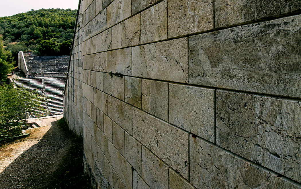 An den Außenmauern des Theaters von Epidaurus beeindruckt die exakten Steinmetzarbeiten der Antike.