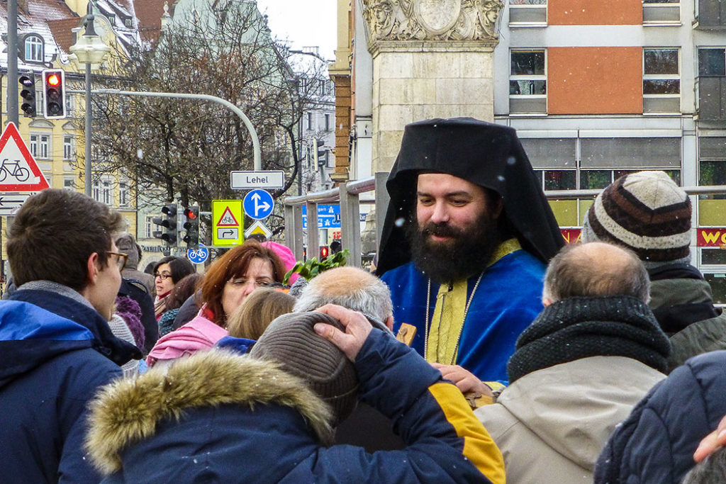 Archimandrit Georgios Siomos reicht den Gläubigen das Holzkreuz.
