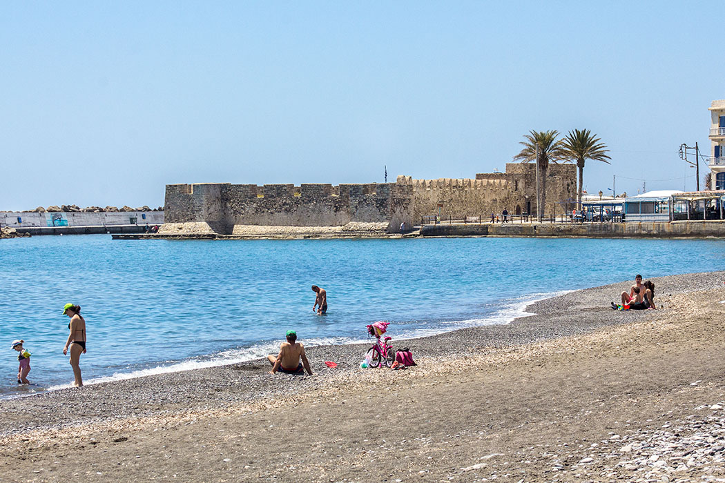Der gepflegte Sand-Kieselstrand beginnt im Zentrum von Ierapetra. Der flachabfallende Strand ist auch für Kinder ideal. Im Hintergrund das Hafenkastell Fort Kalés aus dem 13. Jhd.